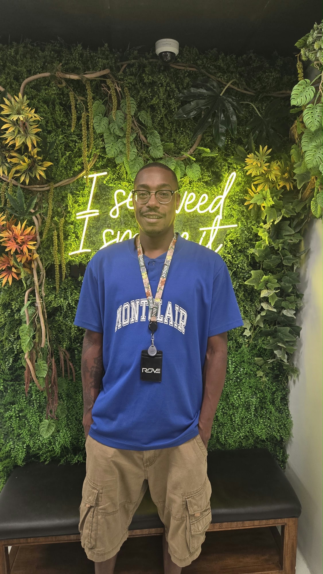 A Hamm & Chaz team member at the plant wall photo spot beneath the neon sign, Jersey City